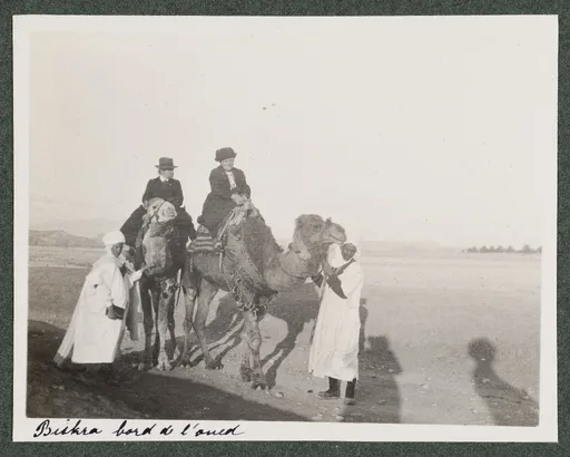 Ottilie W. Roederstein und Jeanne Smith auf Kamelen mit einheimischen Begleitern, Biskra, Bord de l'Oued